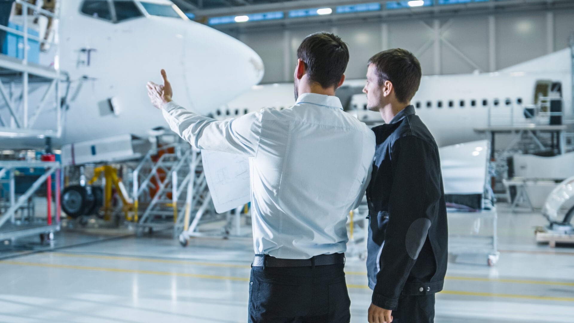 aircraft maintenance worker and engineer having conversation. looking at the airplane.